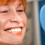 woman in a dental chair looking at her teeth in a mirror