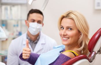 Cheerful woman after dental tratment showing her thumb up.
