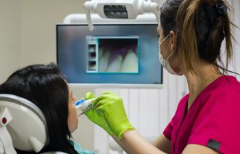 A dentist with intraoral camera examining patient's teeth and gums.