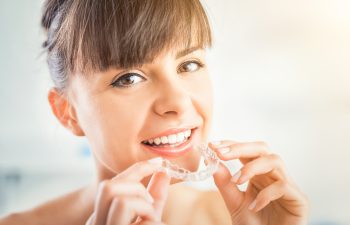 Woman with a perfect smile holding an Invisalign aligner