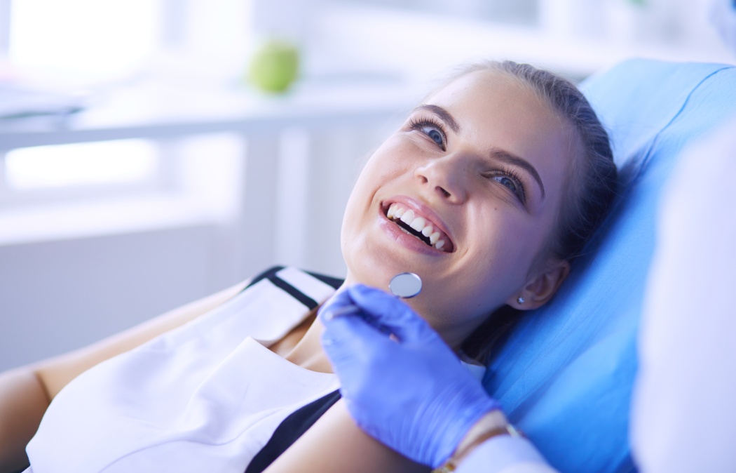Young Female patient with pretty smile examining dental inspection at dentist office.