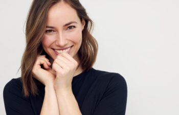Portrait of beautiful young female or woman looking happy and confident in camera. Big smile on her face, looking beautiful standing isolated on white background. Concept: having a secret.