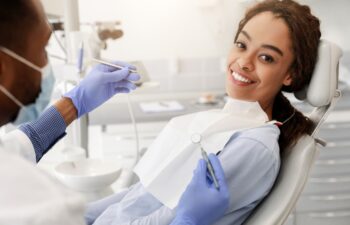 Pretty black happy woman in dentist chair ready for regular check up in modern stomatological clinic